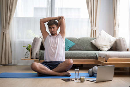 Handsome sporty man stretching arms during morning workout at home. Sport, fitness and healthy lifestyle concept.の写真素材