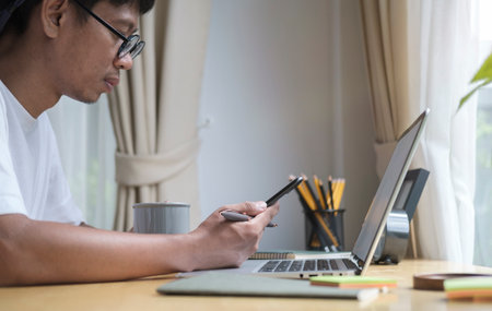 Cropped shot happy asian man sitting on home and using smart phone.の写真素材