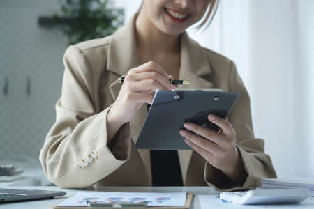 Cropped shot asian businesswoman sitting at office desk and checking business documents.