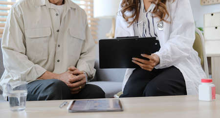 in white medical uniform consult female patient using tablet on consultation