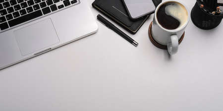 Office desk with smart phone, laptop computer, notebook and coffee cup. Copy space.の写真素材