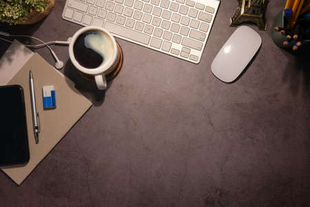 Top view smart phone, coffee cup and stationery on black table. Stylish workplace.