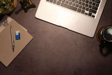 Flat lay laptop computer, coffee cup and stationery on black table with copy space.