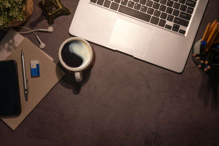 Flat lay laptop computer, smart phone, coffee cup and stationery on black table with copy space.