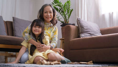 Happy old grandmother hugging little grandchild and smiling at camera. Love and relation of...