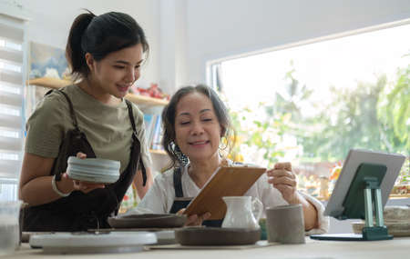 Small business owners preparing  pottery earthenware product for shipping to costumer. E-commerce, online selling, small business and technology concept.の写真素材