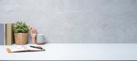 Stylish workplace with books, coffee cup, eyeglasses and potted plant on white table. Copy space for your advertise text.の写真素材