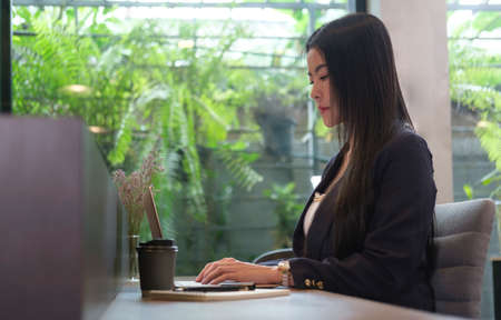 Focused businesswoman looking at laptop screen, typing business email or check media news.の写真素材