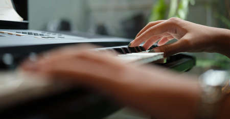 Close up view of young woman playing electric piano at home.の写真素材