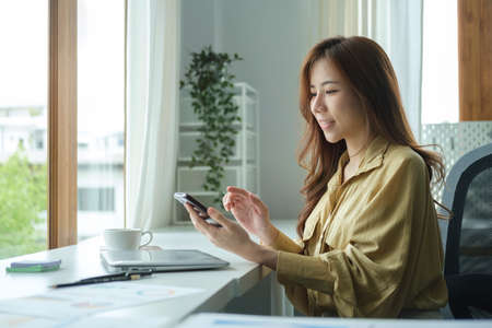 Happy young woman using smart phone for communicating on social media.の写真素材
