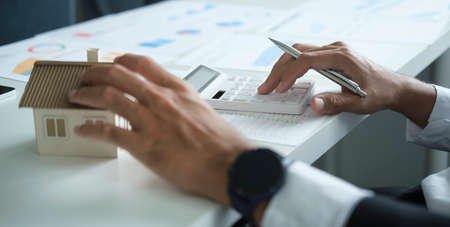 Cropped shot of businessman using calculator, calculating loan of finance and investment for real estate.の写真素材