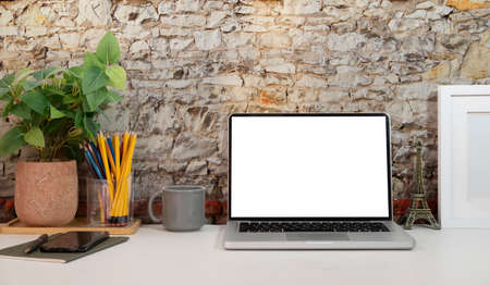 Computer laptop with empty screen, coffee cup, and potted plant on table. Home office.