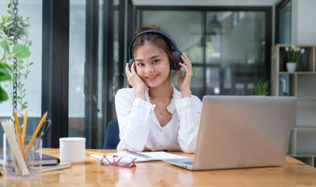 Charming female freelancer wearing headphones and working online with laptop computer.の写真素材