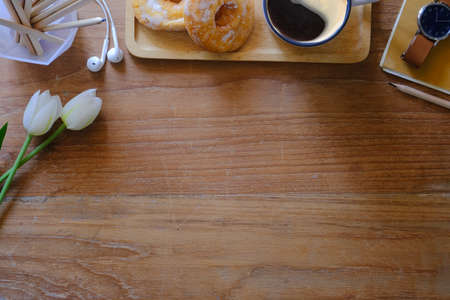 Flat lay coffee cup, white tulips and earphone on wooden table. Top view with copy space.の写真素材