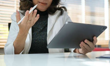 Concentrated middle aged businesswoman reading online information on digital tablet.の写真素材