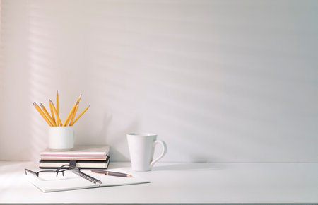 Comfortable workplace with coffee, stationery and houseplant on white table.の写真素材