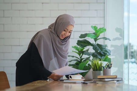 Young Muslim businesswoman using laptop and checking financial reports at her workplace.の写真素材