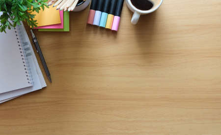Above view stationery, potted plant, and coffee on wooden table. Flat lay, top view with copy space.の写真素材