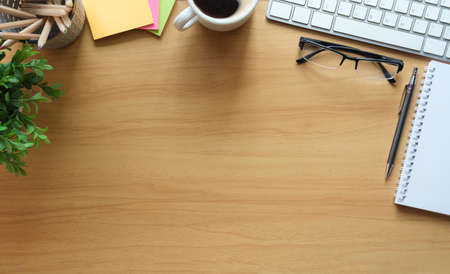 Wooden office desk with notepad, sticky note, glasses, coffee cup and potted plant. Top view, Flat lay with copy space for your text.の写真素材