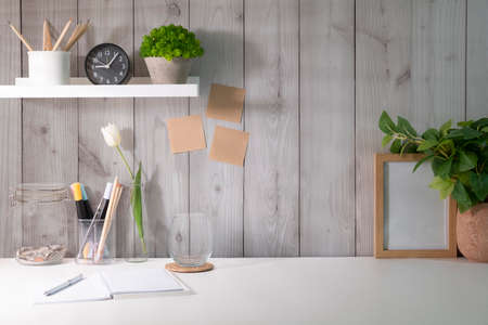 Home office desk with potted plants, stationery and picture frame.の写真素材