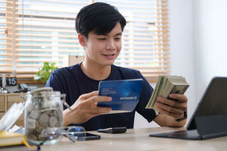 Man holding saving account passbook, calculating domestic bills and managing household expenses expenditures.の写真素材