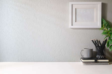 Blank picture frame, coffee cup, notebook and house plant. Home office desk, Copy space for your...