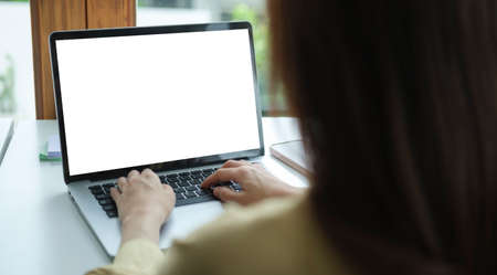 Back view creative woman working with laptop computer while sitting in modern office.