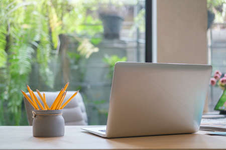 Laptop computer, pencil holder and Supplies on wooden office desk.の写真素材