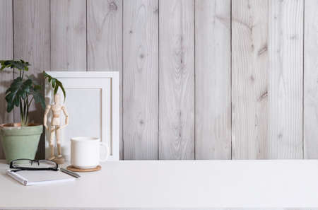 Blank picture frame, coffee cup, houseplant and supplies on white table. Copy space for your advertise text.の写真素材