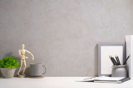Home office desk with cup of coffee, picture frame, houseplant and pencil holder. Copy space for your text.の写真素材