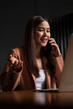 Successful female entrepreneur talking on mobile phone sitting in office.