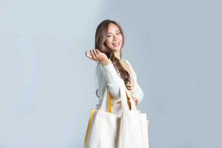 Smiling trendy woman in warm sweater with shopping bags standing on white background.  Black Friday...