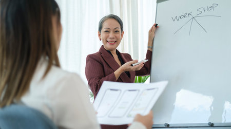 Experienced senior business woman giving a presentation on a flip board in corporate meeting.の写真素材