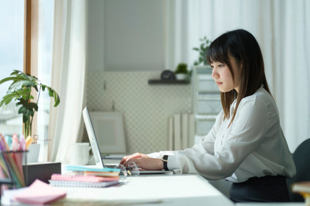 Concentrated start up business woman working on project with laptop at comfortable workplace.の写真素材