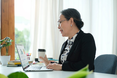 Senior Asian woman working from home with laptop and smart phone. Old woman living and learning online.の写真素材