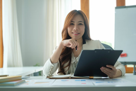 Confident millennial female entrepreneur sitting in her personal office and smiling to camera.の写真素材