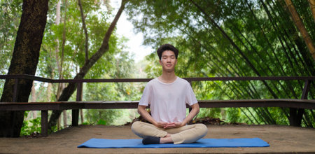 Young man practicing yoga and meditating at open yoga studio with beautiful nature view in background.の写真素材