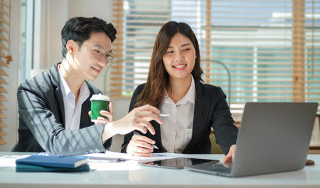 Smiling young businessman explaining online information to his colleagues.の写真素材