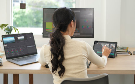 Back view of female video editor  editing video on computer at creative office studio.