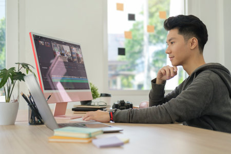 Focused creative man working editing video footage in creative office studio.の写真素材