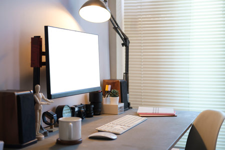 Creative workplace with white blank computer screen,lamp and supplies on black wooden table.の写真素材