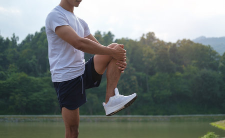 Athletic man stretching legs before jogging in morning. Physical activity, healthy lifestyle concept.の写真素材