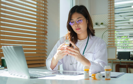 Female doctor holding bottle with pills, working with medical documents at medical office. Medical care, pharmacy concept.の写真素材