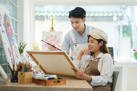 Male and female artist painting  on canvas, working for creative project in bright art workshop.の写真素材