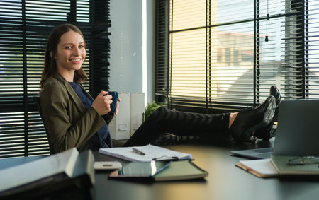 Satisfied caucasian businesswoman  drinking coffee, feeling peaceful resting at workplace.