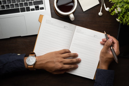 Businessman holding pen writing on blank notepad. Top view, blank screen for your advertise design.の写真素材