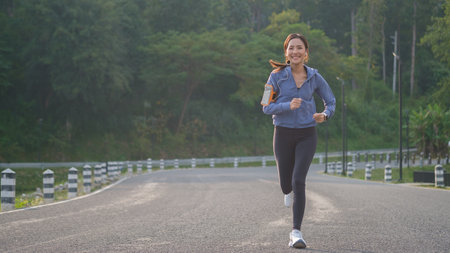 Smiling sporty woman in sportswear jogging in park during sunset.