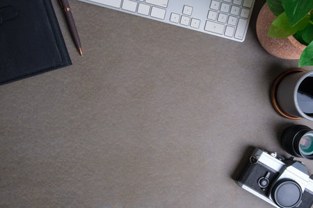 Stylish workspace with notebook, camera and coffee cup on grey table. Copy space for your advertise...