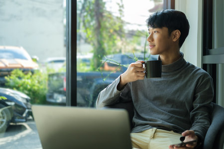 Thoughtful start up business man  drinking morning coffee and looking away.の写真素材