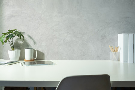 Modern workplace with tablet, books, houseplant and coffee cup on white table. Copy space for your text and product display .の写真素材